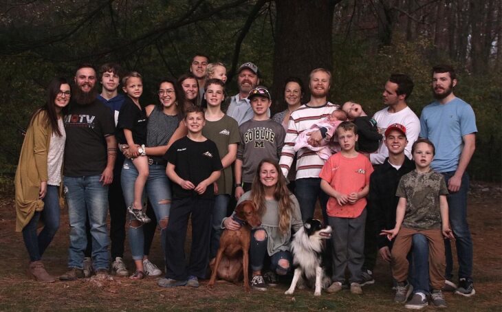 Familia de 14 integrantes posando para una fotografía en medio del bosque 