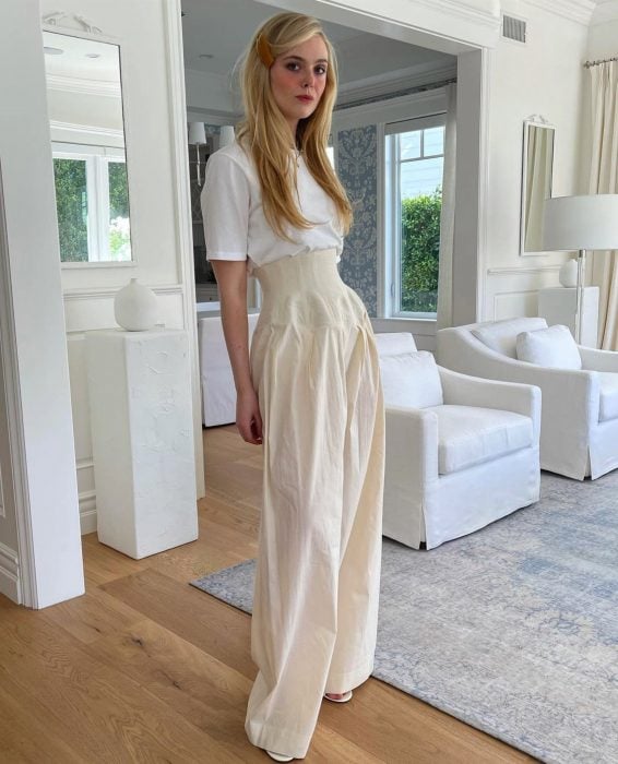 Elle Fanning posando en una sala de estar vestida de color blanco 