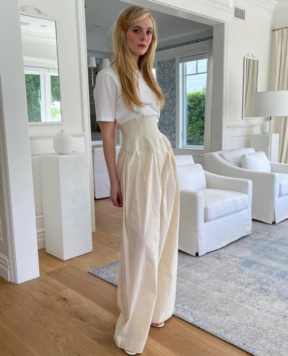 Elle Fanning posando en una sala de estar vestida de color blanco 