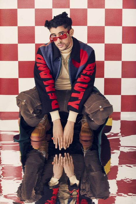 Singer Bad Bunny posing in a photograph where the background is red with white 