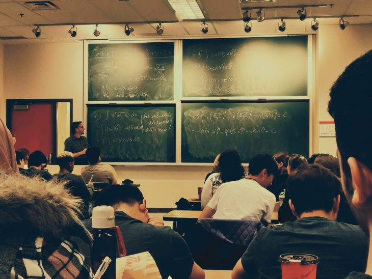 Teacher in front of the blackboard;  Teacher carries his student's baby so he can take her class;  his picture goes viral