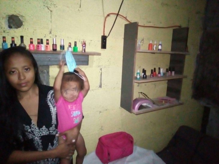 mujer con una niña en los brazos en su casa donde monto un salón de uñas en Mérida Yucatán 