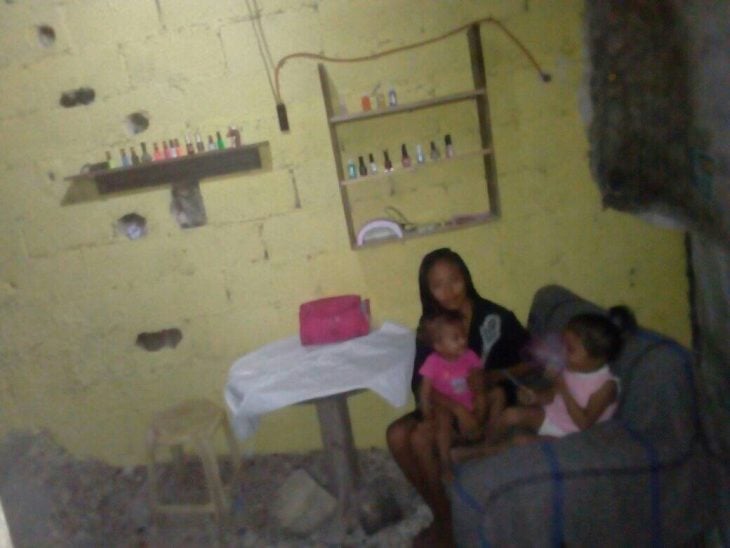 mujer sentada rodeada de sus hijas en un pequeño salón de uñas que montó en su casa 