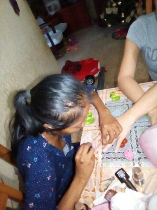 mujer poniendo esmalte en las manos de una mujer 