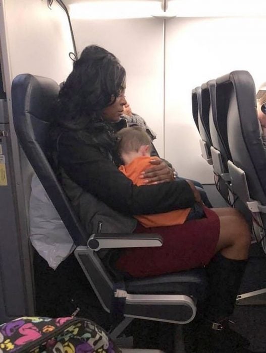 Mujer sosteniendo a un bebé en brazos durante un vuelo en avión