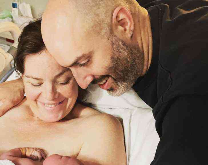 Woman and her husband watching their baby after birth 