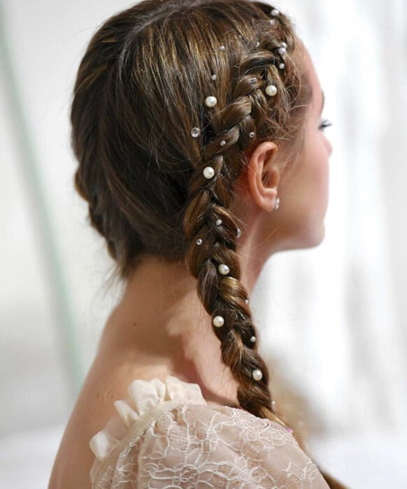 chica castaña con trenzas y perlas en el cabello