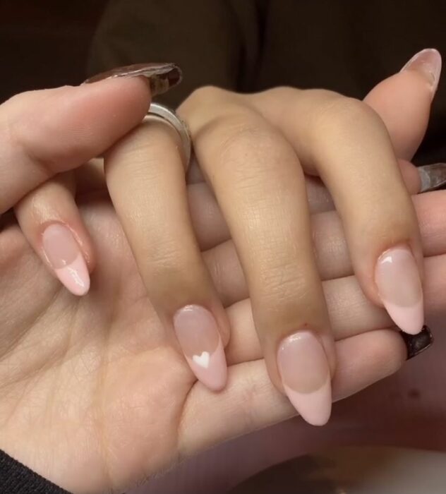 uñas con punta rosa pastel y un corazón blanco pequeño