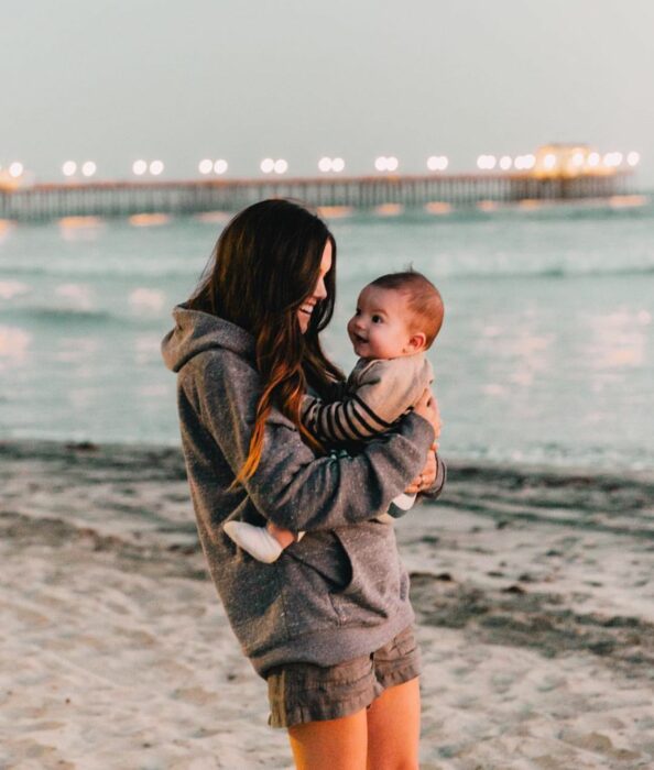 mamá cargando a bebé en la playa