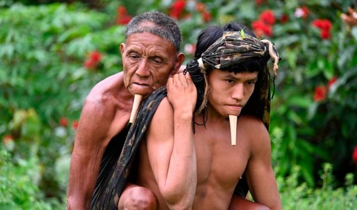 Nativo brasileño cargando a su padre en la espalda 