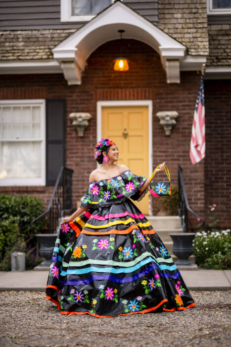 Chica frente a su casa posando un vestido hecho con cintas adhesivas de colores