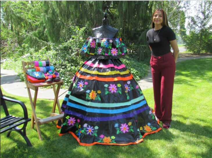 Larissa Leon posing next to her folk dress made with duct tape