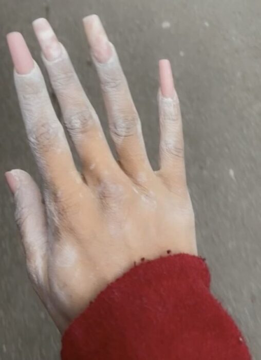 photograph of a woman's hand with long nails full of plaster 