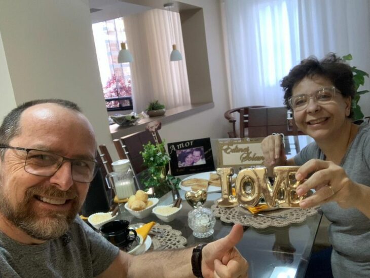 selfie de una pareja donde la esposa muestra un letrero de love en su mano 