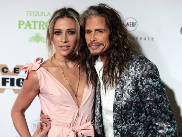 Steven Tyler and Aimee Preston embracing as they smile for a photo 