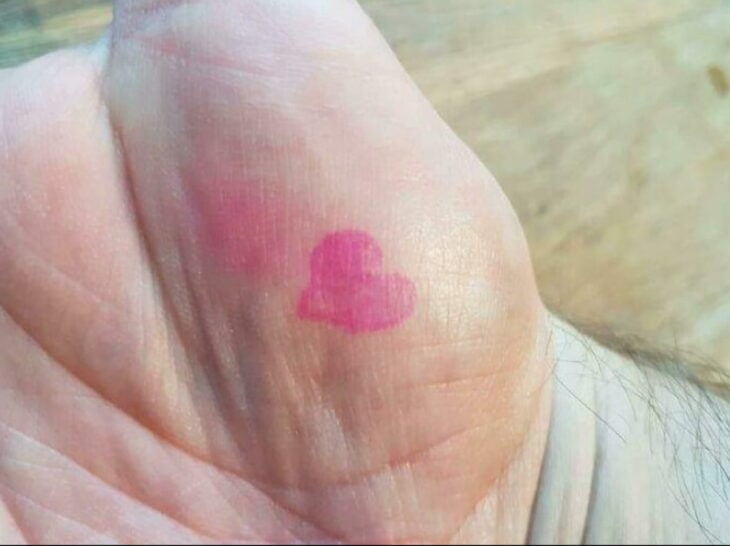 mano de un hombre con el dibujo de un corazón rosa 