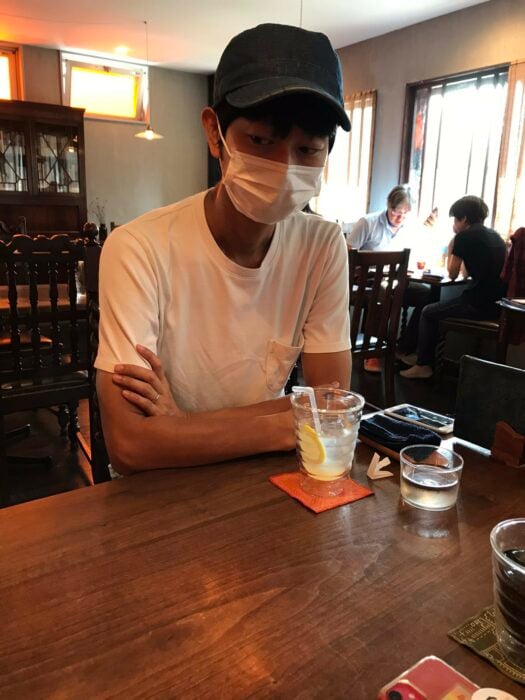 hombre japonés sentado en un restaurante con una bebida en la mesa 