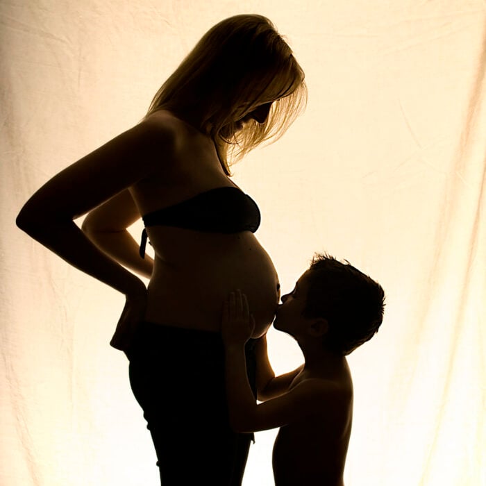 imagen de un niño besando la panza de su mamá embarazada 