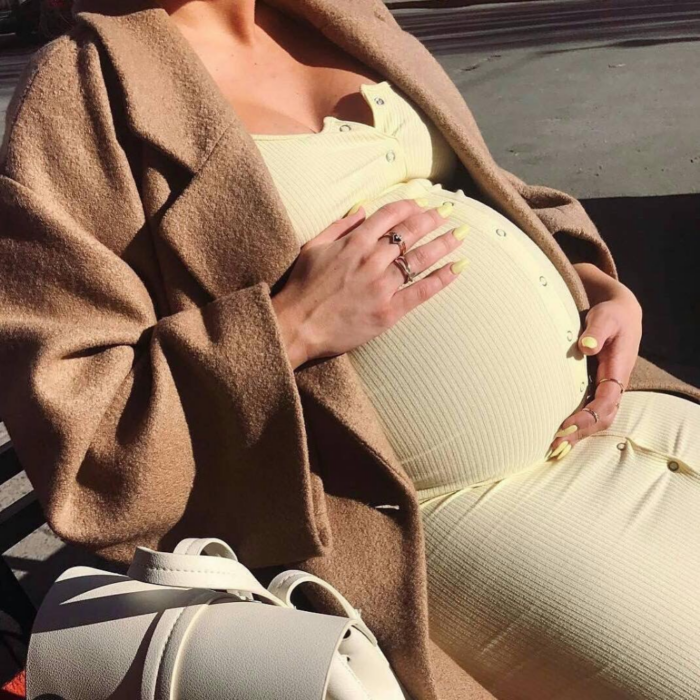 imagen de una mujer embarazada sentada tocando su barriga 