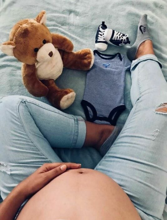 imagen de una chica embarazada con ropita de bebé 