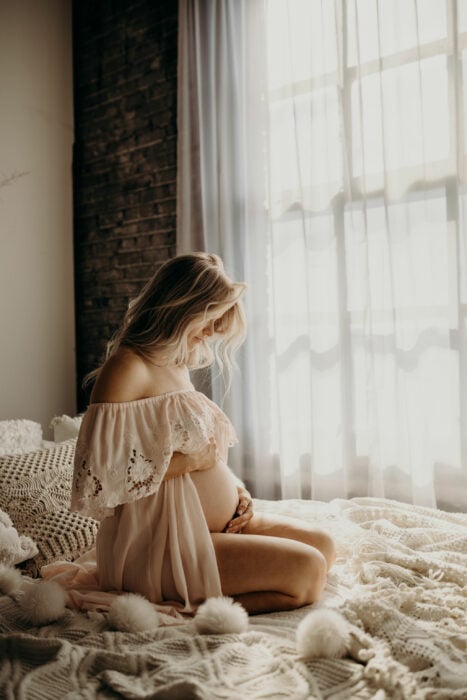 Imagen de una mujer embarazada sentada en una cama 