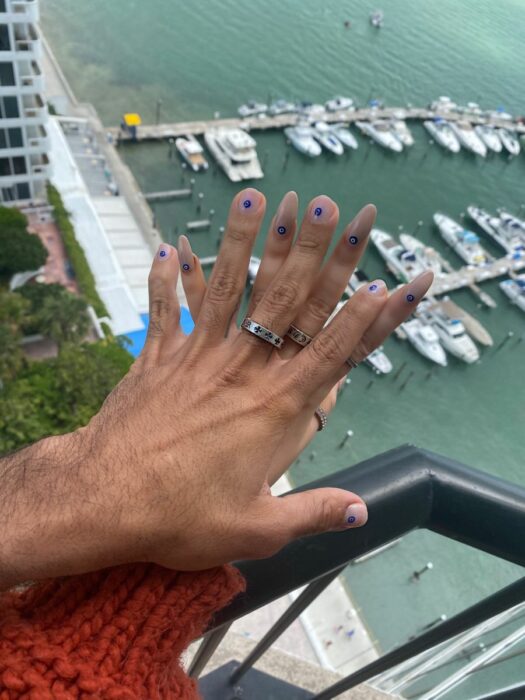 imagen de una pareja con sus manos frente a un balcón en el mar 
