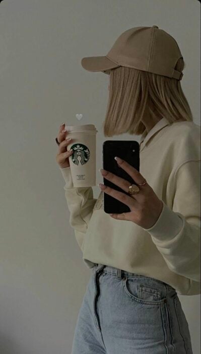 Chica tomando una foto mientras se toma un café 