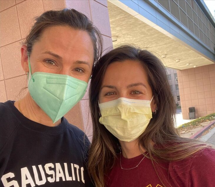 Jennifer Garner a lado de una persona del sector salud fuera de un hospital