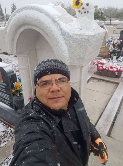 selfie de un hombre frente a la tumba de su esposa con un muñeco de nieve