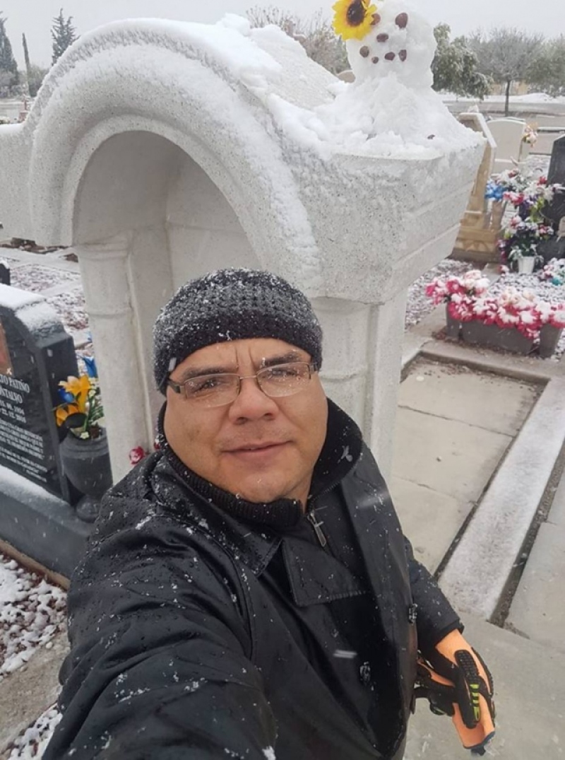 selfie of a man in front of his wife's grave with a snowman