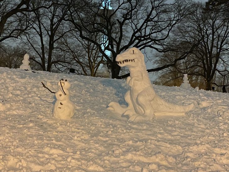 figura de nieve de T-Rex siguiendo a un muñeco de nieve 