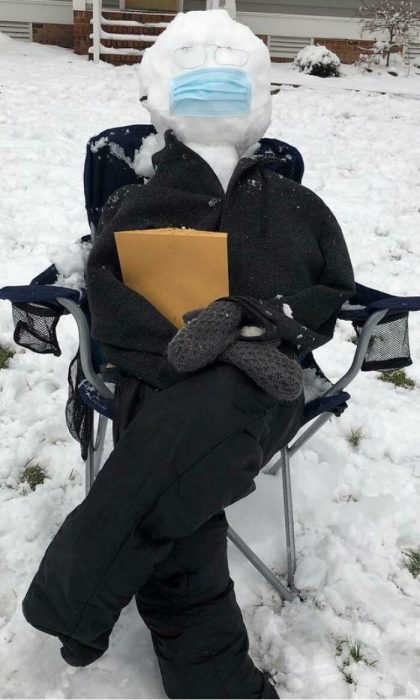 Muñeco de nieve sentado en una silla con ropa, usando lentes y cubrebocas 