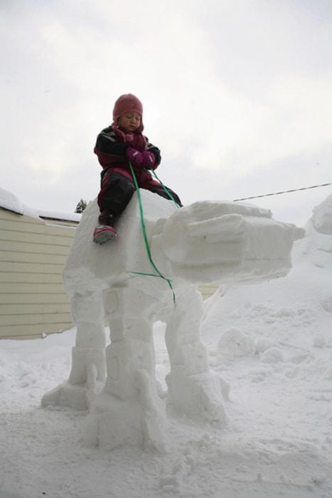niña montada sobre una figura de nieve n forma de un montable 