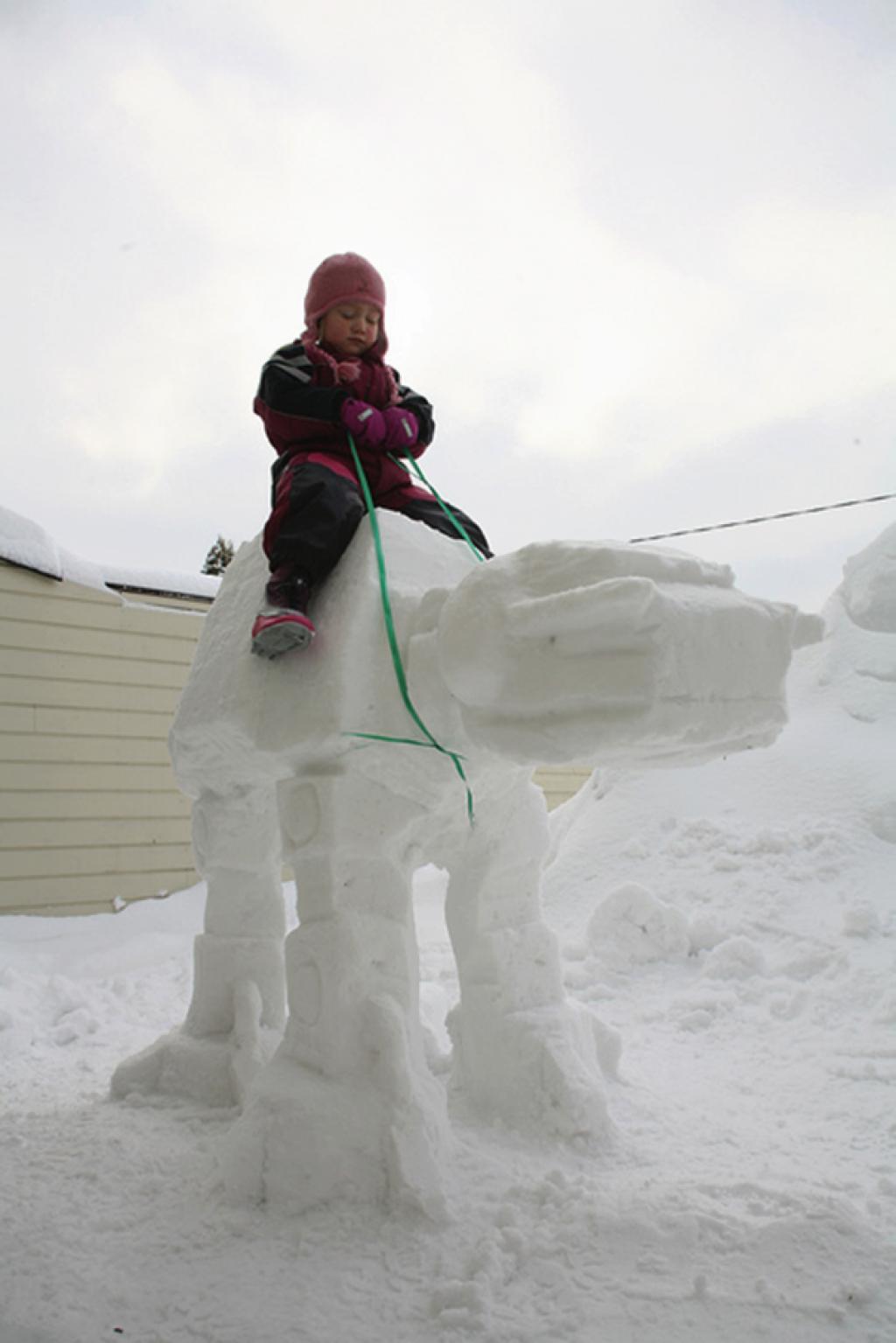 girl riding on a snow figure in the form of a mountable 