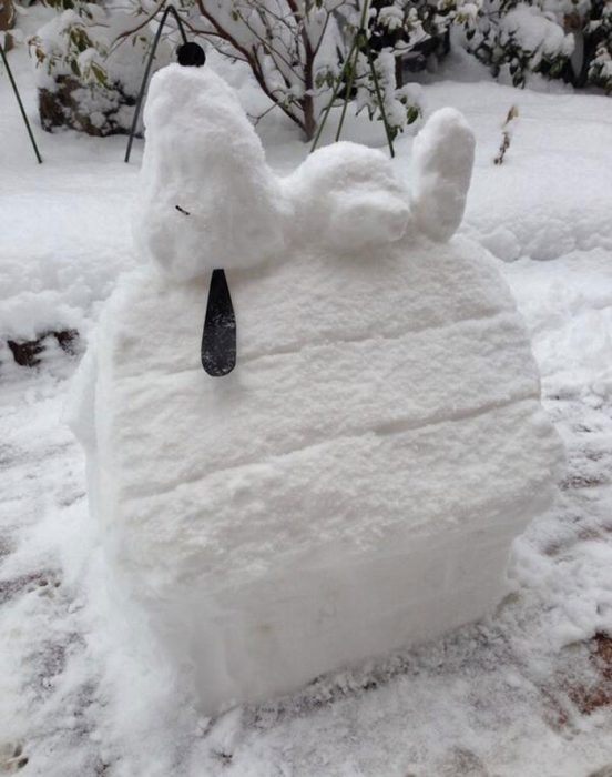 figura de nieve de snoopy acostado sobre su casa en el patio 