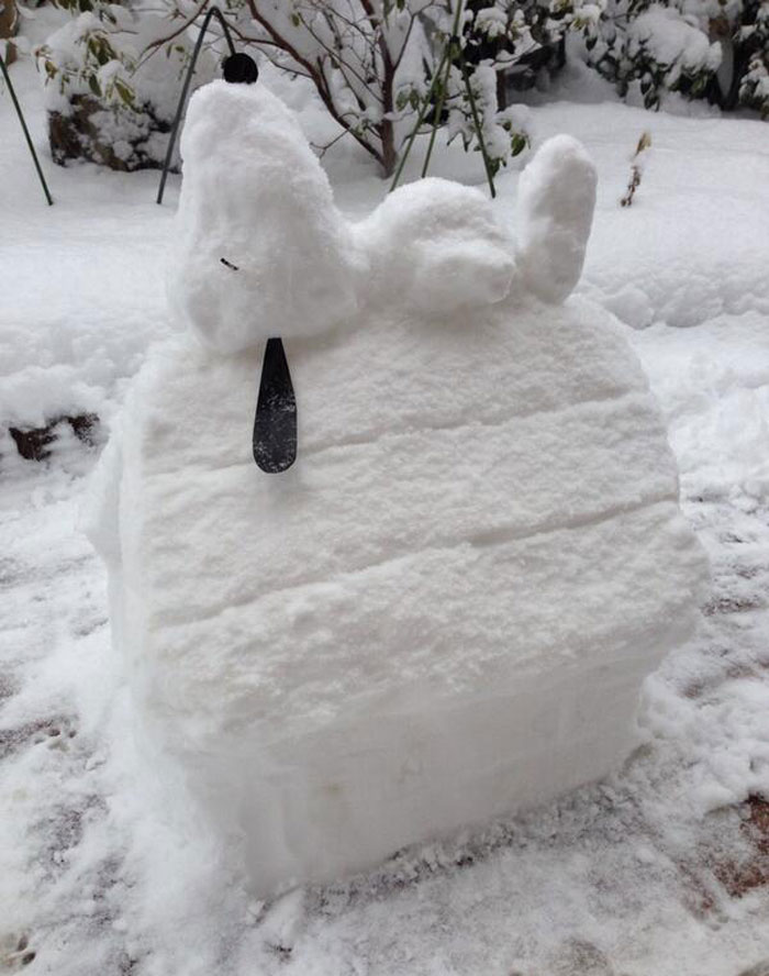 snow figure of snoopy lying on his house in the yard 