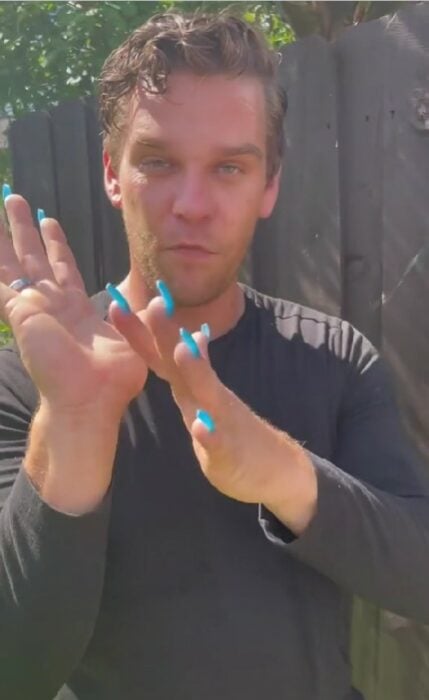 hombre mostrando la parte baja de la palma de la mano con uñas acrílicas azules 