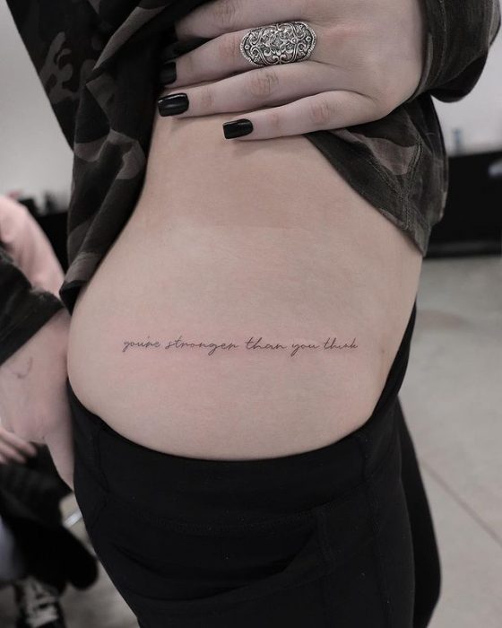 Chica mostrando un tatuaje en la cintura 
