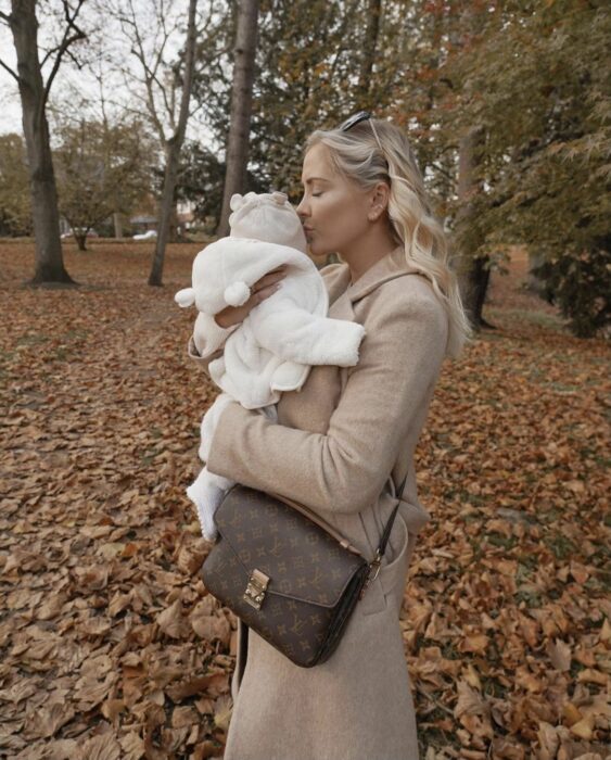 mamá cargando a su bebé en el otoño