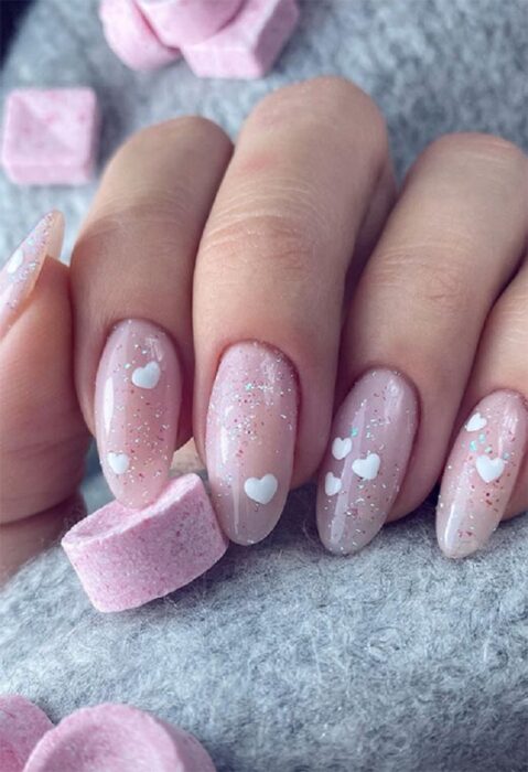 uñas ovaladas brillantes con corazones blancos