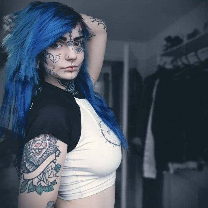 blue-haired woman with tattoos on her face