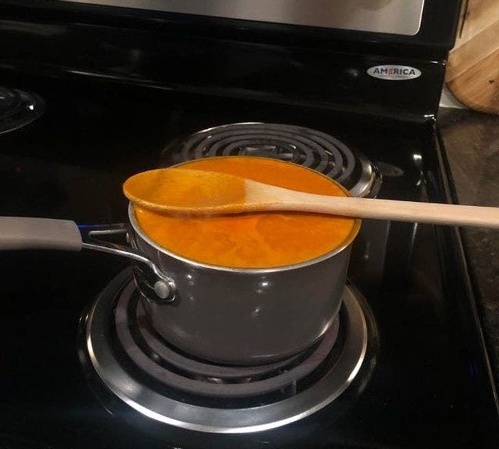 sartén con sopa hasta el tope en la llama de una estufa 
