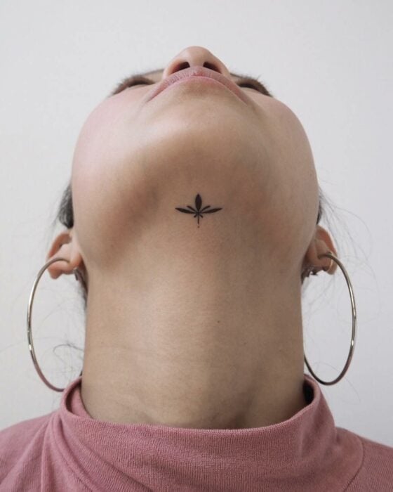 cara de una mujer con un tatuaje de rama debajo de la barbilla