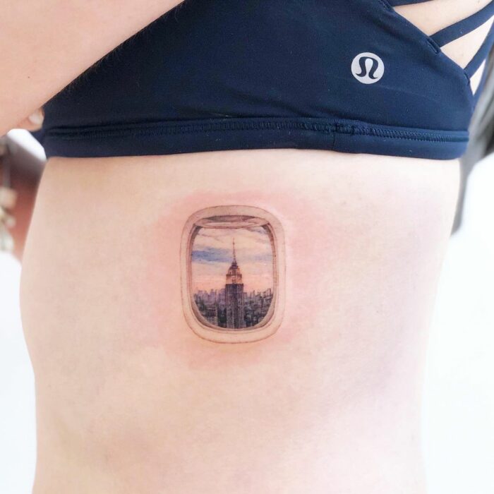 Tattoo of a photo through an airplane window on a person's rib 