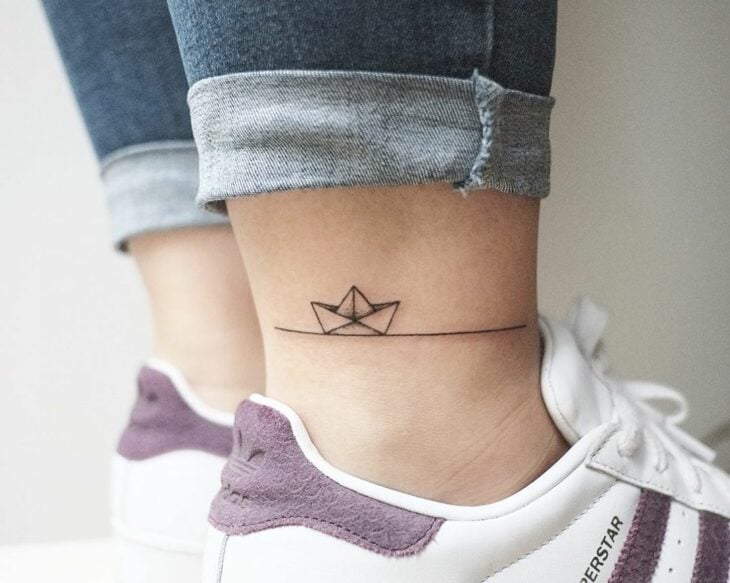 foto de un tatuaje de barquito de papel en un tobillo