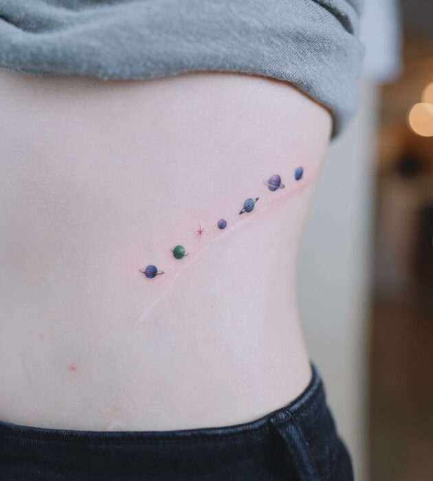 tattoo of various colored planets on the side of a woman's body