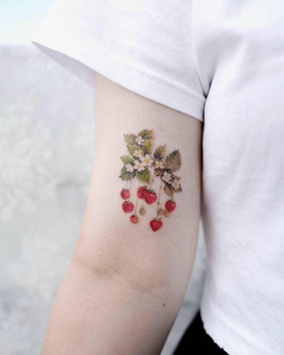 tatuaje de una fragaria de fresas en el brazo de una chica 