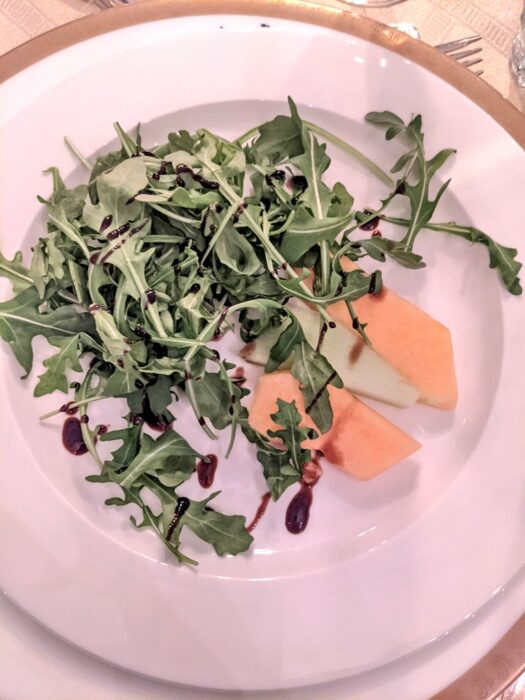 platillo de comida con hojas de rúcula y unos trozos de melón