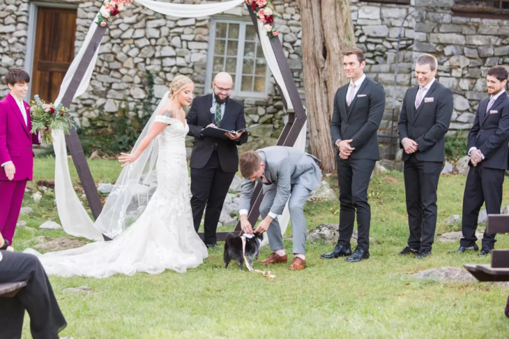 hombre agarrando los anillos del lomo de su perro durante la ceremonia de su boda