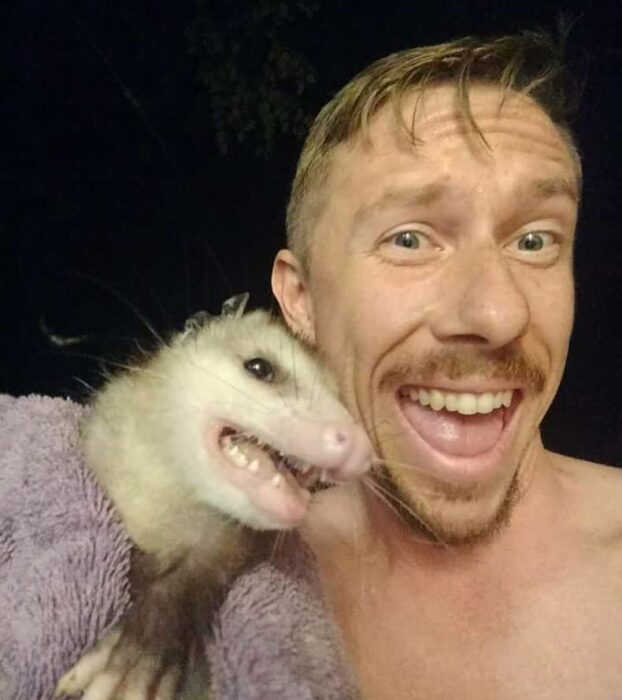 a man next to a possum smiling 